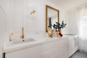 ein weißes Badezimmer mit Waschbecken und Spiegel in der Unterkunft Suite de Luxe à 10 min de Paris - Sauna, Cinéma in Bagneux