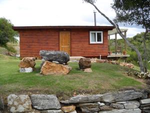 a log cabin with rocks in front of a house at El Ahora in El Eden