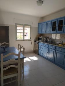a kitchen with blue cabinets and a table and chairs at Casa da Alzira T2 in Vila Nova de Milfontes