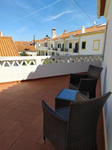 a patio with chairs and a table on a balcony at Casa da Alzira T2 in Vila Nova de Milfontes