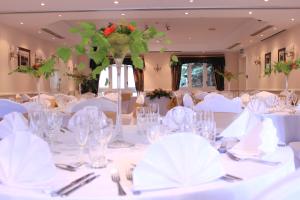 a room filled with tables with white table settings at The Devil's Punchbowl Hotel in Hindhead