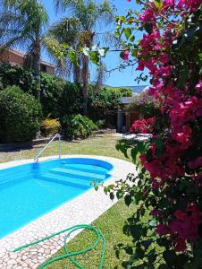 einen Pool im Garten mit rosa Blumen in der Unterkunft CASA RIO TERCERO Cordoba Argentina in Río Tercero