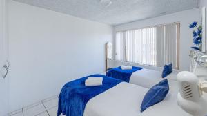 ストロイスバーイにあるBlue Whaleのベッドルーム1室(青いシーツと窓付きのベッド2台付)