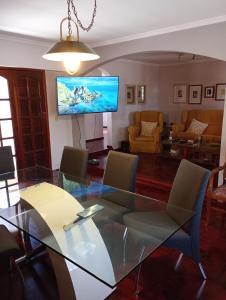 ein Esszimmer mit einem Glastisch und einem TV in der Unterkunft CASA RIO TERCERO Cordoba Argentina in Río Tercero