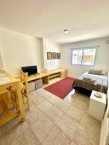 a bedroom with a bed and a desk and a television at Departamentos Caranday in San Luis