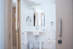 Baño blanco con lavabo y espejo en Aparthotel Acualandia, en Peñíscola