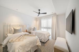 a white bedroom with two beds and a ceiling fan at Allure 301 condo in Bridgetown +19 photos