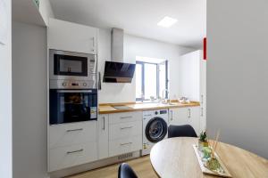 カリェタにあるVila Sun House Aのキッチン(白いキャビネット、テーブル、電子レンジ付) +12枚の写真