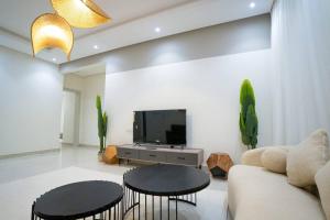a living room with two tables and a tv at 005 - Saudi - Elegant apartment in Riyadh (Noor) in Al Hofuf