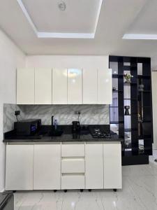 a kitchen with white cabinets and a black counter top at Cozy one bedroom apartment in Abuja