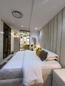 a large white bed in a bedroom with a wall at Cozy one bedroom apartment in Abuja