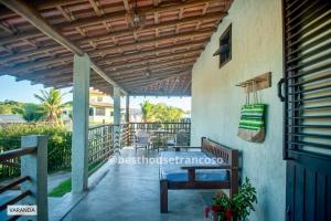a porch with a wooden pergola and a bench at Best House Trancoso in Porto Seguro