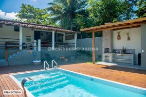 a swimming pool with a patio and a house at Best House Trancoso in Porto Seguro