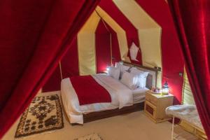 a bedroom with a red and yellow tent with a bed at Merzouga dunes erg chabbi Camp in Merzouga