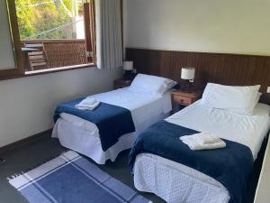 a hotel room with two beds and a window at Apartamento Charmoso com vista para o mar in Ilhabela