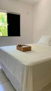 a white bed with a box on top of it at Aconchegante Apartamento in Porto Seguro