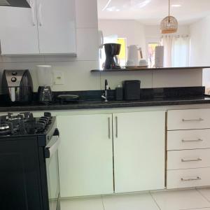 a kitchen with white cabinets and a black counter top at Aconchegante Apartamento in Porto Seguro