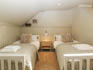 モートン・イン・マーシュにあるCotswold Houseのベッドが2つとランプ付きのテーブルがある部屋