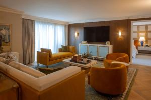 a living room with a couch and chairs and a television at Regent Santa Monica Beach by IHG in Los Angeles