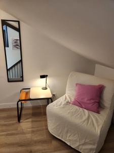 een slaapkamer met een bed met een roze kussen en een tafel bij Studio downtown, proche ville close, Wifi in Concarneau