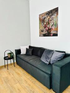 a green couch in a living room with a painting at Wohnung im Zentrum von Neuss - Estia Living in Neuss