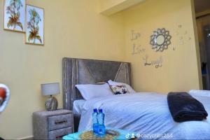 a bedroom with a bed and a table with bottles on it at The Cozy Cranny, Kamakis in Ruiru
