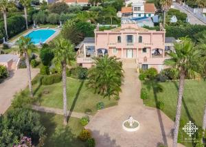 ein Luftblick auf ein rosafarbenes Haus mit Palmen in der Unterkunft Villa Festosa - Luxury retreat by the beach in Villaggio Azzurro