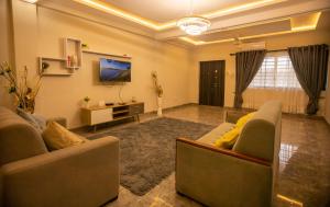 un salon avec deux canapés et une télévision dans l'établissement Agape Villa, à Sékondi