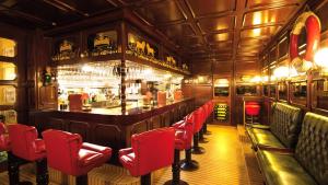 un bar con sedie rosse in un ristorante di Hotel Appartement Landhaus Stutzi - Hotel Strandperle a Cuxhaven