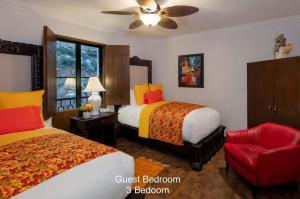 a bedroom with two beds and a red chair at 4BD Oceanfront Unit Vista Encantada - Cabo in Cabo San Lucas