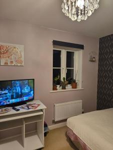 ein Schlafzimmer mit einem Schreibtisch mit einem Fernseher und einem Bett in der Unterkunft Desborough home for short term rent in Desborough