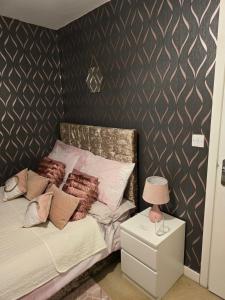 ein Schlafzimmer mit einem Bett mit Kissen und einem Nachttisch in der Unterkunft Desborough home for short term rent in Desborough