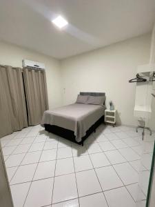 a bedroom with a bed and a white tiled floor at Apartamento amplo e bem localizado in Porto Velho