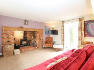 a living room with a red couch and a fireplace at Willow Cottage in Norwich
