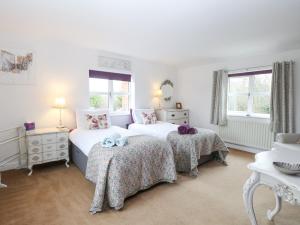 a white bedroom with two beds and two tables at Willow Cottage in Norwich