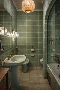 a green tiled bathroom with a sink and a toilet at Pergola Boutique Hotel in Cascais