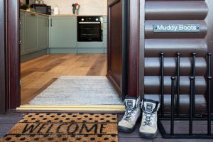 a welcome mat in front of a door with two shoes at Sandmartin Lodge a lakeshore haven at Pine Lake Resort in Carnforth
