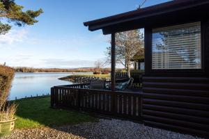 a house with a balcony and a lake at Sandmartin Lodge a lakeshore haven at Pine Lake Resort in Carnforth