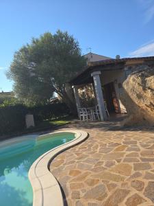 a swimming pool with a stone walkway next to a house at Bellissima villa piscina 8 pax 1500 mt dal mare FMP-CAT01-PI in Monte Petrosu