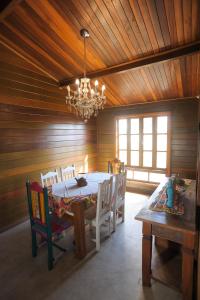 una sala da pranzo con tavolo, sedie e lampadario di CASA DE MADEIRA a Conselheiro Lafaiete