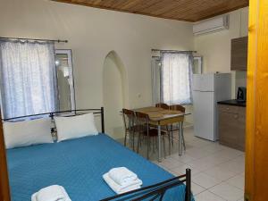 a bedroom with a bed and a kitchen with a table at Nefeli House in Loutsa