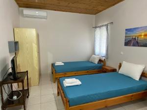 a room with two beds and a television in it at Nefeli House in Loutsa