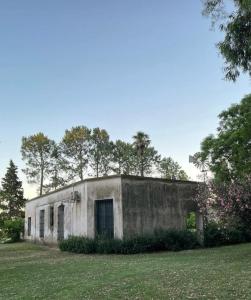 un antiguo edificio en un campo con árboles en el fondo en Chacra del Molino, en Navarro 36 fotos más