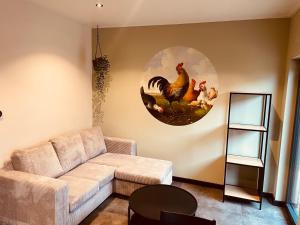 a living room with a couch and a painting of chickens at De kraaiende haan in Liessel
