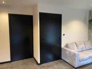 a living room with two black doors and a couch at De kraaiende haan in Liessel