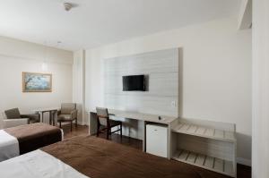 a hotel room with a bed and a desk with a tv at Hotel D'sintra in Balneário Camboriú +37 photos