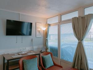 a room with a desk with chairs and a television at The Chalet in Skegness +2 photos