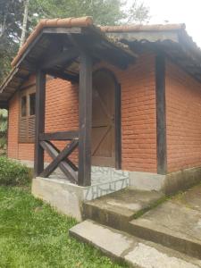 ein kleines Backsteingebäude mit einer Holztür in der Unterkunft Chalé 2 in Nova Friburgo