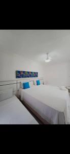 two white beds with blue pillows in a bedroom at Apartamento próximo à praia de taperapuã in Porto Seguro +6 photos