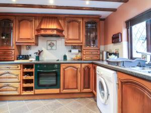 eine Küche mit Holzschränken, einer Waschmaschine und einem Trockner in der Unterkunft Old Farm Cottage in Ilfracombe
